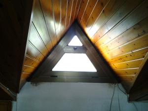 Fabricación de ventana batiente, en aluminio color bronce, en forma de triángulo para buhardilla de vivienda.
